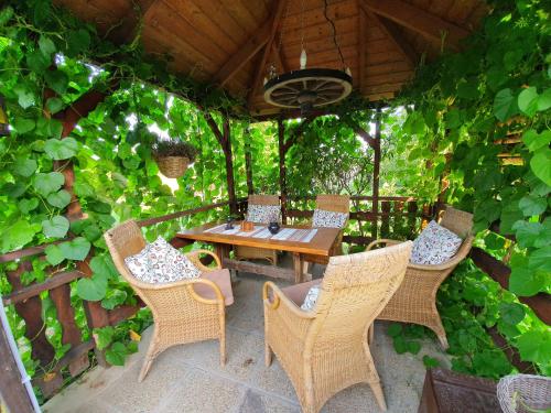 乔保克Dália Apartmanok的庭院配有木桌、椅子和藤蔓