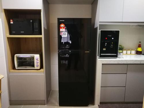 普特拉贾亚Bayu D'Awan Muslim Homestay Putrajaya的微波炉旁厨房里的黑冰箱