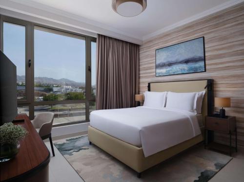 马斯喀特DoubleTree by Hilton Muscat Qurum的卧室设有白色的床和大窗户