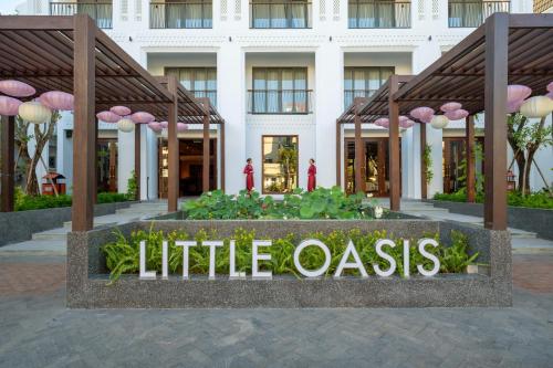 会安Little Oasis - An Eco Friendly Hotel & Spa的建筑前的小绿洲的标志