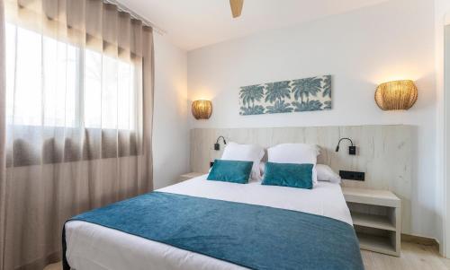 卡门港Bakour Lanzarote Splash的一间卧室配有一张带蓝色枕头的床和一扇窗户。
