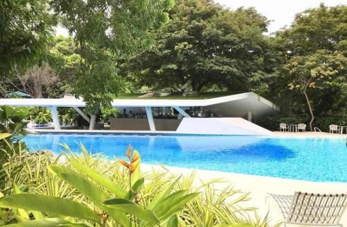 MaribagoTAMBULI SEASIDE LIVING STAYCATION的一座带房子和树木的蓝色游泳池
