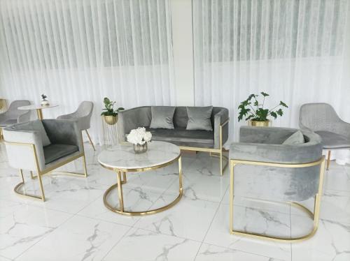 曼谷Golden Nest Hotel Suvarnabhumi的客厅配有沙发、椅子和桌子