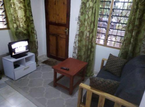 姆特瓦帕Moringa Garden Cottage的客厅配有电视、沙发和桌子