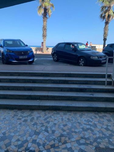 鲁西隆地区卡内Studio au Front de la Mer的两辆汽车停在海滩附近的楼梯旁