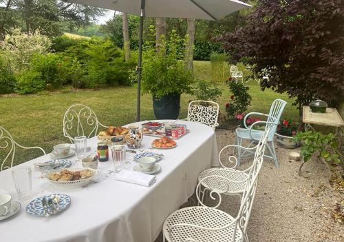 Bresse-sur-GrosneLa Rochelière的一张桌子,上面有食物,还有椅子和雨伞