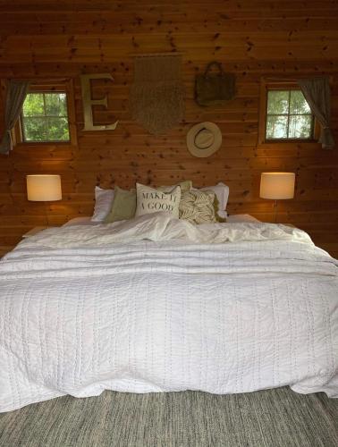 希恩Koselig hytte langs elven的木制房间一张大白床,配有两盏灯