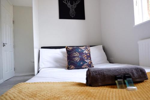 剑桥COMFORTABLE 4-Bed HOME WITH 3 BATHROOMS AND FREE PARKING!的一张带枕头的床和两个遥控器