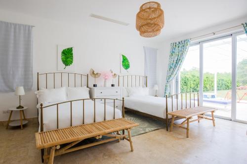 蓬塔卡纳Tranquil Lakefront 5-Bedroom Villa with Cook, Maid, Golf Cart, and Beach Access in Punta Cana的一间白色卧室,配有一张床和两把椅子