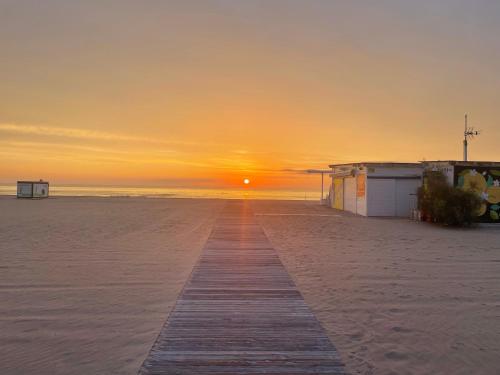 甘迪亚海滩Apartamento TalaMar Gandia Playa的日落时在海滩上木板路