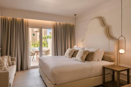 拉瑟Thalassa Boutique Hotel - Adults Only的一间带一张白色大床的卧室和一个阳台