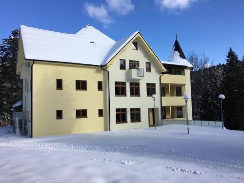 Nová ľubovňaPenzión Probstner的一座大黄色的建筑,地面上积雪