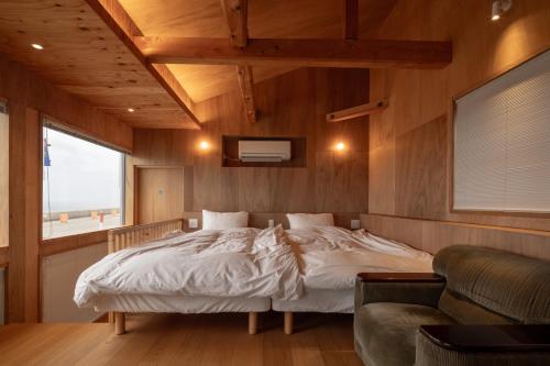 七尾OH!TOMARI的一间卧室配有一张床、一张沙发和一个窗口