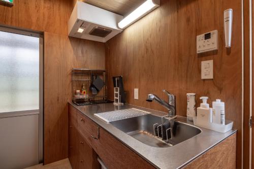 七尾OH!TOMARI的厨房设有不锈钢水槽和木墙