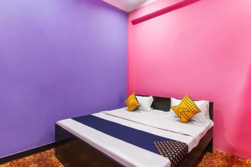 KākoriOYO 78880 Rajdhani Hotel的卧室设有粉红色和紫色的墙壁和一张床