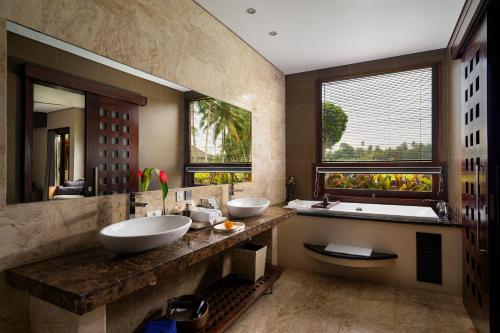 乌布巴厘岛豪华别墅式酒店的一间带两个盥洗盆和浴缸的浴室以及大窗户。