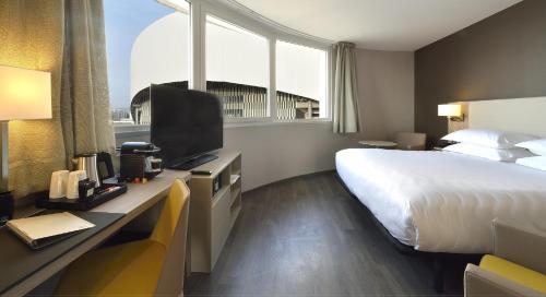 马赛AC Hotel by Marriott Marseille Prado Vélodrome的酒店客房配有一张床和一张书桌及一台电视