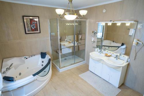 苏恰瓦爱丽丝旅馆的带浴缸、两个盥洗盆和淋浴的浴室。