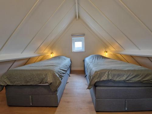 尼乌波特Premium Holidays - modern vacation home in a vacation park in Nieuwpoort的阁楼卧室设有两张床和窗户。