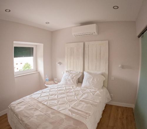塞亚Casa do Bairro的一间卧室配有一张带白色床单的床和一扇窗户。