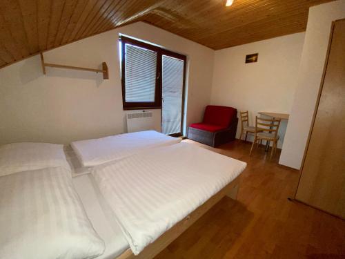 维尼Apartmány Alma的一间卧室配有两张床和一张红色椅子的桌子