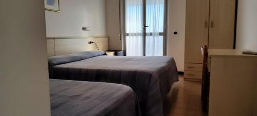朱利亚诺瓦Hotel Holiday的酒店客房设有两张床和窗户。