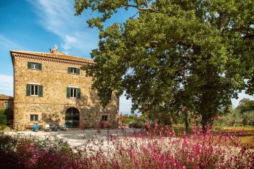 蒙塔尔奇诺Villa Le Prata - Farm House & Winery - Adults Only的一座大型石头建筑,前面有粉红色的花朵