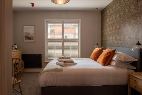 ManningtreeThe Crown Pub and Hotel的一间卧室配有带橙色枕头的床和窗户。