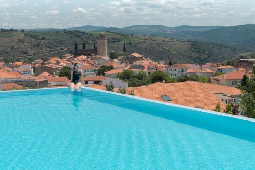 弗雷舒德埃什帕达阿辛塔Hotel Freixo Douro Superior的站在游泳池边俯瞰城市的女人