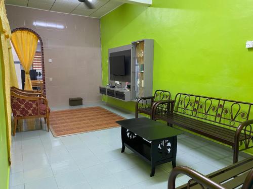 马六甲83 Homestay的客厅设有绿色的墙壁和电视。