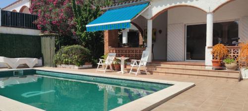帕尔斯Chalet Sol y Sombra的一座房子旁边的游泳池,上面有蓝色遮阳篷