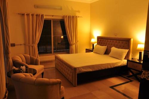 伊斯兰堡Reina Boutique Hotel - G6的一间卧室配有一张床、两把椅子和一个窗户