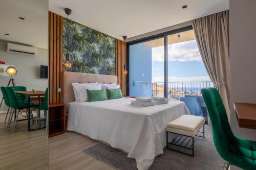 丰沙尔Atlântico Azul的酒店客房带一张床、一张桌子和椅子