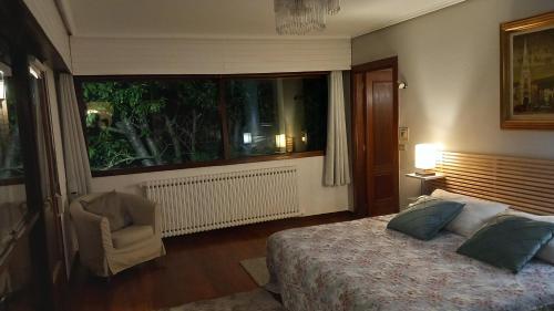 格乔Azkorri Beach House的卧室配有床、椅子和窗户。