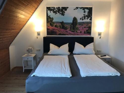 伯根Naturhotel Hof Ehlers的卧室配有一张大床,墙上挂有绘画作品