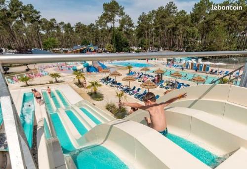 波讷地区圣朱利安Plage de Contis, Camping SIBLU 3*, parc aquatique, piscines chauffées.的游泳池水滑梯上的男孩