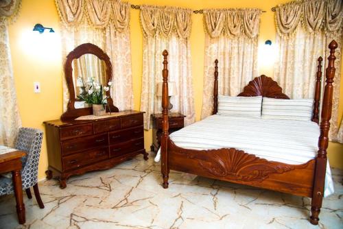尼格瑞尔Dela de-Rose Guest House Negril Jamaica的一间卧室配有一张床、梳妆台和镜子