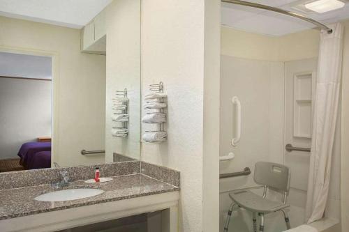 威奇托Economy Hotel Wichita 2的一间带水槽、淋浴和椅子的浴室