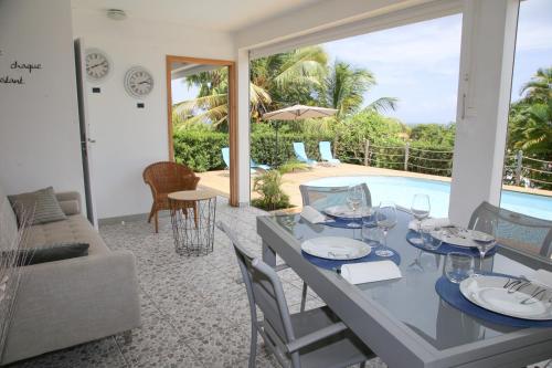 圣安尼L Orchidée Bleue, bas de villa, vue mer, piscine privée的一间带桌椅的用餐室和一个游泳池