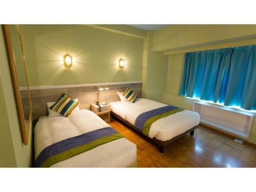 境港市Hotel AreaOne Sakaiminato Marina - Vacation STAY 81704v的客房设有两张床和一扇带蓝色窗帘的窗户。