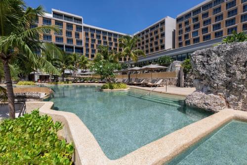 麦克坦Sheraton Cebu Mactan Resort的一座游泳池,其背景是一座度假村