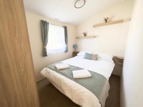 塞顿港Edinburgh - Seton Sands-Salsa Caravan-Pet Friendly的一间卧室配有一张床,上面有两条毛巾