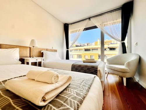 里斯本Luz Benfica Apartment的一间卧室设有两张床、一把椅子和一个窗户。