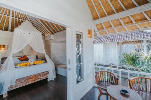 蓝梦岛Paluh Beach Huts的卧室配有一张床和一张桌子及椅子
