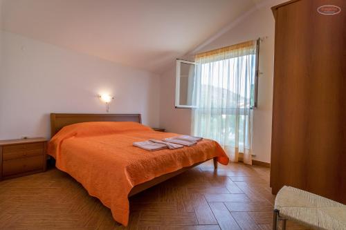 拉布Apartments by the sea Supetarska Draga - Gornja, Rab - 21380的一间卧室配有带橙色床单的床和窗户。