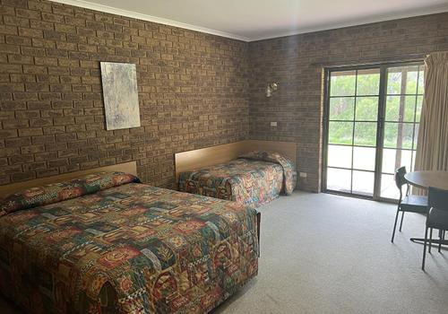 托克姆沃尔Tocumwal Early Settlers Motel的一间卧室设有两张床、一张桌子和一个窗口