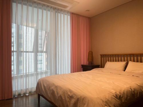 釜山Haeundae Luxury House的一间卧室设有一张床和一个大窗户