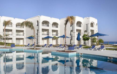 马特鲁港Cleopatra Luxury Resort Sidi Heneish - North Coast的一个带椅子和遮阳伞的游泳池的度假酒店