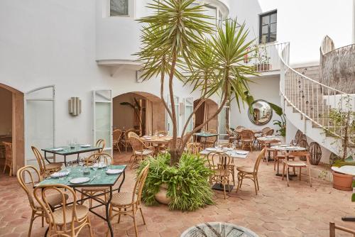 马略卡岛帕尔马Puro Hotel Oasis Urbano的一间设有桌椅的餐厅,种植了棕榈树
