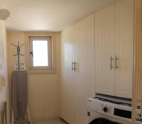 梅内乌Captivating Lake & Oceanview Getaway House的厨房配有白色橱柜和窗户。